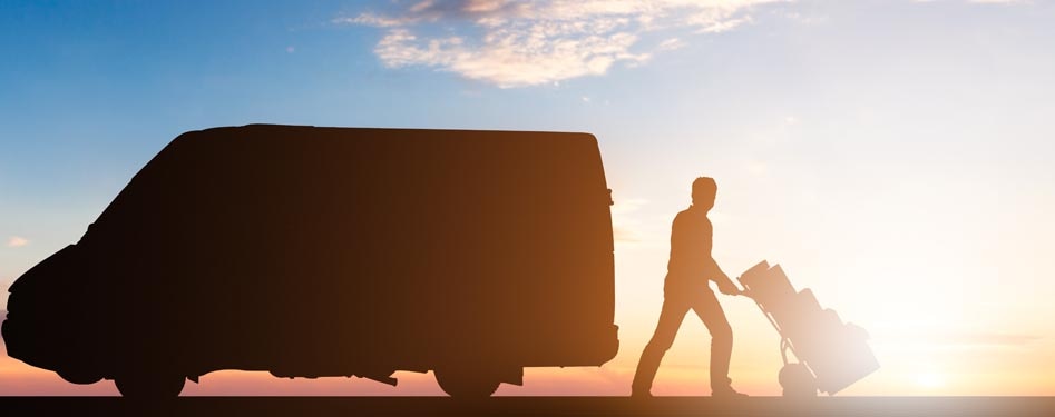 Man with dolly in front of truck at sunset